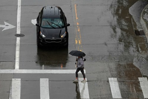 FILE - A pedestrian crosses the street in front of a car May 12, 2024, in Denver. (AP Photo/David Zalubowski, File)