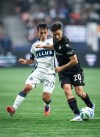 Vancouver Whitecaps' Andres Cubas (20) and Vancouver FC's Nicolas Mezquida (20) vie for the ball during the second half of the Canadian Championship final soccer match in Vancouver, on Wednesday, Oct. 1, 2025. THE CANADIAN PRESS/Ethan Cairns
