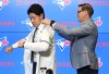Kazuma Okamoto, the Toronto Blue Jays newest signing dons a jersey with the assistance of Jays general manager Ross Atkins at an introductory press conference at Rogers Centre in Toronto on Tuesday, Jan. 6, 2026. THE CANADIAN PRESS/Jon Blacker