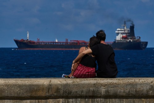 A couple sit on a seawall while watching a tanker ship exit the bay of Havana, Cuba, Saturday, Feb. 14, 2026. (AP Photo/Ramon Espinosa)