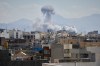 People watches from rooftop as a plume of smoke rises after a strike in Tehran, Iran, Sunday, March 1, 2026. (AP Photo/Vahid Salemi)