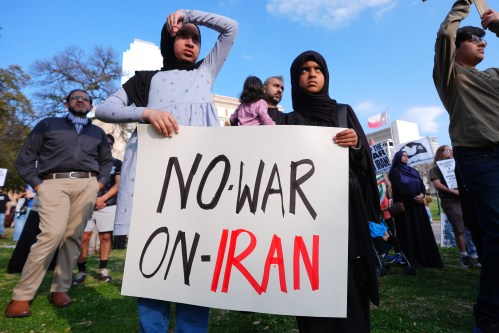 Children hold a sign protesting war against Iran during an antiwar demonstration at Dealey Plaza in downtown Dallas, Sunday, March 1, 2026. (AP Photo/LM Otero)