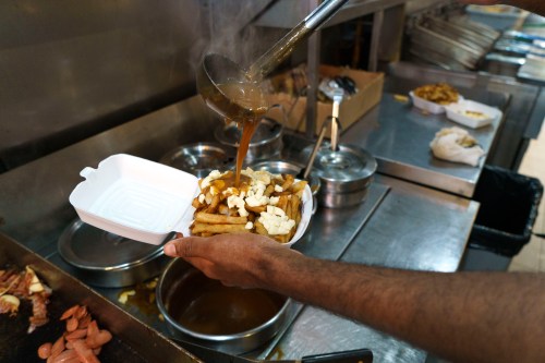 A cook prepares a poutine at La Banquise restaurant in Montreal on Tuesday, May 18, 2021. THE CANADIAN PRESS/Paul Chiasson