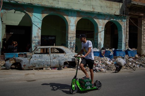 A man rides a scooter past a wrecked car and garbage during a blackout in Havana, Wednesday, March 4, 2026. (AP Photo/Ramon Espinosa)