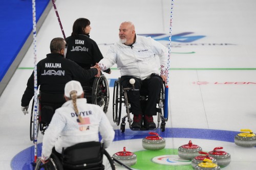 Steve Emt, right, and Laura Dwyer, of the United States, and Yoji Nakajima, left, and Aki Ogawa, of Japan, greet each other after their wheelchair curling mixed doubles round robin session at the 2026 Winter Paralympics, in Cortina d'Ampezzo, Italy, Thursday, March 5, 2026. (AP Photo/Evgeniy Maloletka)