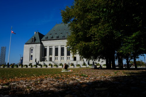 People take a break in front of the Supreme Court of Canada building in Ottawa on Monday, Oct. 6, 2025. THE CANADIAN PRESS/Sean Kilpatrick.