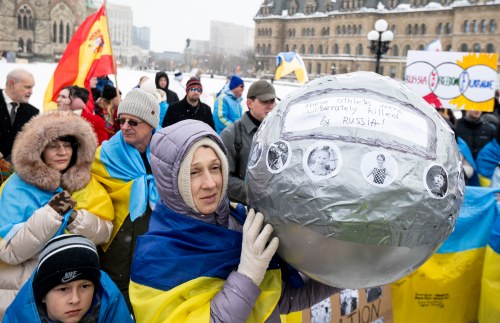 A pro-Ukrainian demonstrator holds a helmet with pictures of deceased Ukrainian athletes during a rally on Parliament Hill in Ottawa, on Sunday, Feb. 22, 2026. The helmet replicates one worn by Ukrainian skeleton racer Vladyslav Heraskevych who was disqualified during the 2026 Olympic Winter Games. THE CANADIAN PRESS/Spencer Colby