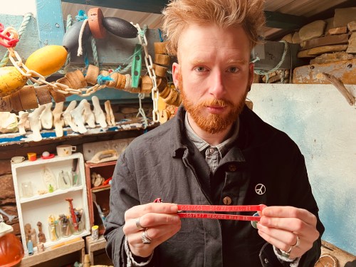 David Warner is shown on Feb. 20 in Scotland. Warner is seen holding up two plastic lobster tags stamped with 