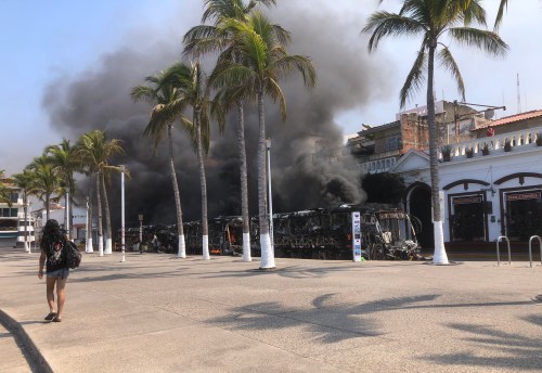 A person walks near a burned out bus on the boardwalk in the tourist area of Puerto Vallarta, Mexico in this image provided by Canadian Marc Edge. THE CANADIAN PRESS/Handout-Marc Edge
(Mandatory credit)