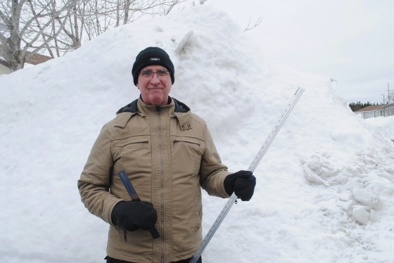 Sixty-two-year-old Lloyd Leaman stands in front of a towering snow bank in Paradise, N.L., on Wednesday. (Sarah Smellie / The Canadian Press)