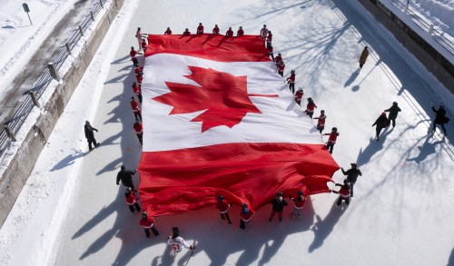 Local youth skate with a large Canadian flag on the Rideau Canal to launch celebrations for the 60th Anniversary of the National Flag of Canada Day, Friday, Feb. 14, 2025 in Ottawa. THE CANADIAN PRESS/Adrian Wyld