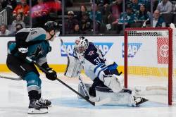 Winnipeg Jets goaltender Connor Hellebuyck (37) blocks a shot by San Jose Sharks center Philipp Kurashev (96) during the third period of an NHL hockey game, Sunday, March 1, 2026, in San Jose, Calif. (Godofredo A. Vásquez / The Associated Press)