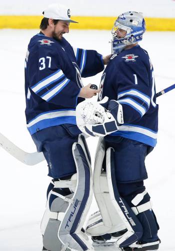 John Woods / THE CANADIAN PRESS FILES
                                Winnipeg Jets goaltender Connor Hellebuyck, left, congratulates team mate Eric Comrie on his first NHL shutout after a game 2022.