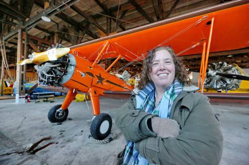 Y MATT GOERZEN / THE BRANDON SUN
                                Commonwealth Air Training Plan Museum director general Zoe McQuinn poses in front of a 1943-built Boeing Stearman Kaydet, a recent addition to the historic hanger.