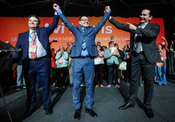 Avi Lewis, centre, who was proclaimed as the new leader of the NDP, celebrates with former interim leader Don Davies, left, and Manitoba premier Wab Kinew at the party convention in Winnipeg Sunday. (John Woods / The Canadian Press)