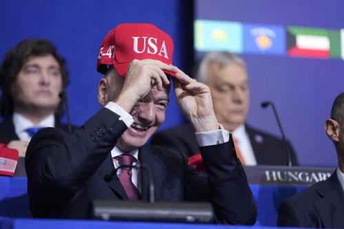 Giovanni Vincenzo Infantino, president of FIFA, tries out a USA hat during a Board of Peace meeting at the U.S. Institute of Peace, Thursday, Feb. 19, 2026, in Washington. (AP Photo/Mark Schiefelbein)