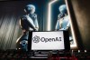 FILE - The OpenAI logo is displayed on a cellphone with an image on a computer monitor generated by ChatGPT's Dall-E text-to-image model, Dec. 8, 2023, in Boston. (AP Photo/Michael Dwyer, File)