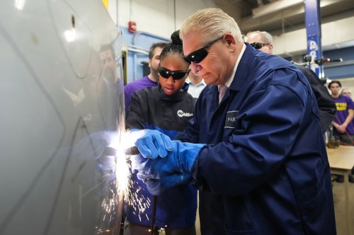 Ontario Premier Doug Ford, right, gets help from Grade 11 student Shannon Williams, 16, as they practise plasma welding on a car hood while visiting St. Mary Catholic Secondary School in Pickering, Ont., on Wednesday, March 8, 2023. THE CANADIAN PRESS/Nathan Denette