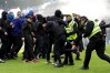 Police officer and stewards force fans back after they invaded the pitch following a penalty shoot out after the Scottish Cup quarterfinal soccer match between Rangers and Celtic, in Glasgow, Scotland, Sunday March 8, 2026. (Steve Welsh/PA via AP)
