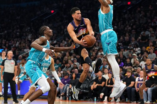 Phoenix Suns guard Devin Booker drives between Charlotte Hornets forward Moussa Diabate, guard Josh Green (10) and forward Miles Bridges during the first half of an NBA basketball game, Sunday, March 8, 2026, in Phoenix. (AP Photo/Rick Scuteri)