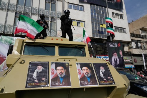 FILE - Policemen stand on top of their car with pictures of the late Iranian Supreme Leader Ayatollah Ali Khamenei, right and left, and his son Ayatollah Mojtaba Khamenei, the successor to him, center, during a rally to support him in Tehran, Iran, March 9, 2026. (AP Photo/Vahid Salemi, File)