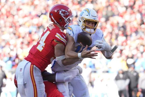 FILE - Los Angeles Chargers quarterback Justin Herbert, right, bobbles the ball as he is hit by Kansas City Chiefs linebacker Leo Chenal during the second half of an NFL football game Sunday, Dec. 14, 2025, in Kansas City, Mo. (AP Photo/Ed Zurga, File)
