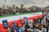 Houthi supporters hold posters of Iran's late Supreme Leader Ayatollah Ali Khamenei, who was killed in an attack by Israel and the U.S., next to a giant Iranian flag as they protest the war on Iran, in Sanaa, Yemen, Friday, March 6, 2026. (AP Photo/Osamah Abdulrahman)