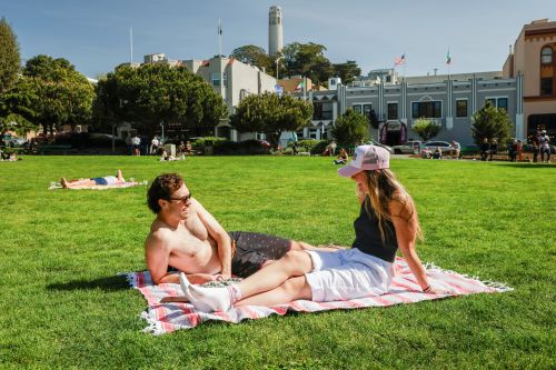 Nick Gardetto, left, and Madi Hirsch lounge in the sun at Washington Square during a heat wave in San Francisco, Sunday, March 15, 2026. (Brontë Wittpenn/San Francisco Chronicle via AP)