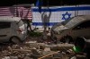 Israeli authorities hang Israeli and U.S. flags at the site struck by an Iranian missile that killed two people, in Ramat Gan, Israel, Wednesday, March 18, 2026. (AP Photo/Oded Balilty)