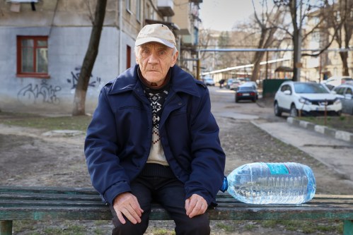 Valentin Belischii, 73 years-old, pauses on a bench before climbing the stairs to his fourth floor apartment with a container of water he bought in Balti, Moldova, Tuesday, March 17, 2026. (AP Photo/Aurel Obreja)
