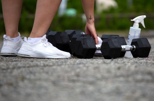 A woman disinfects weights during a physically-distanced outdoor workout at F45 Port Moody in Port Moody, B.C. on Thursday, April 29, 2021. THE CANADIAN PRESS/Marissa Tiel