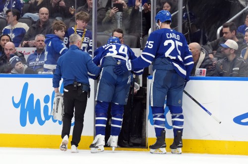 Maple Leafs Auston Matthews (34) is helped off the ice after being injured by Anaheim Ducks Radko Gudas (7) during an NHL game in Toronto on March 12, 2026. THE CANADIAN PRESS/Nathan Denette