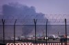 Planes are parked at Dubai International Airport as smoke rises in the background after a drone struck a fuel tank early morning, forcing the temporary suspension of flights, in Dubai, United Arab Emirates, Monday, March 16, 2026. (AP Photo)