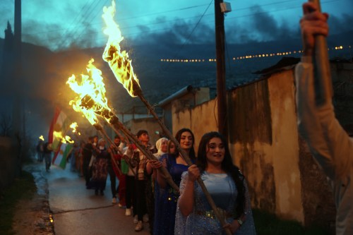 Syrian Kurds hold lit torches as they celebrate Nowruz, the Persian New Year, in the village of Basuta in the Afrin countryside, Syria, Friday, March 20, 2026. (AP Photo/Ghaith Alsayed)