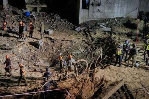 Israeli security forces and rescue teams inspect the crater left by an Iranian missile in Arad, southern Israel, Sunday, March 22, 2026. (AP Photo/Ohad Zwigenberg)