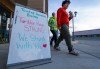 Residents walk past a sign outside a local bistro stating 