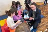 Manitoba Finance Minister Adrien Sala hands out shoes to children at Linwood Childcare Centre in Winnipeg on March 20, 2026, as part of a pre-budget news conference on childcare funding. THE CANADIAN PRESS/Steve Lambert