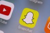FILE- This Aug. 9, 2017, file photo shows the Youtube, left, and Snapchat apps on a mobile device in New York. (AP Photo/Richard Drew, File)