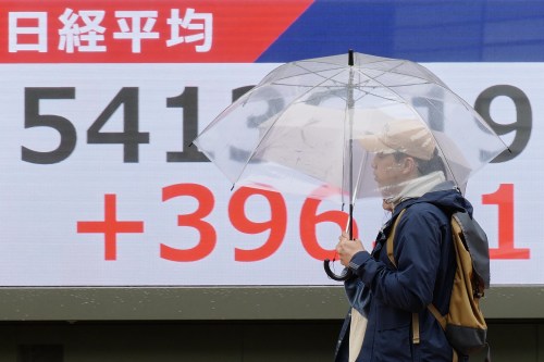 Persons walk in front of an electronic stock board showing Japan's Nikkei index at a securities firm Thursday, April 2, 2026, in Tokyo. (AP Photo/Eugene Hoshiko)