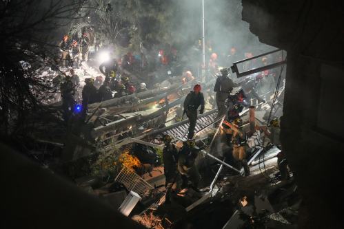 Israeli security forces and rescue teams work amid the rubble of a residential building struck by an Iranian missile in Haifa, Israel, Sunday, April 5, 2026. (AP Photo/Ariel Schalit)