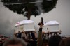 A gunman fires his gun as men carry the coffins with the bodies of Pierre Mouawad, an official with the anti-Hezbollah Lebanese Forces party, and his wife during their funeral in Yahshush, in Lebanon, Tuesday, April 7, 2026. (AP Photo/Emilio Morenatti)