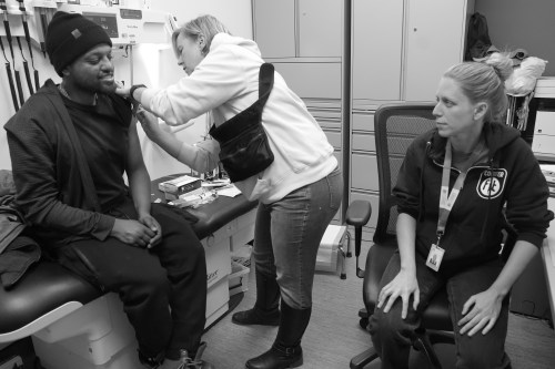 Karen Elmira, a registered nurse, gives service user Yohannes an inoculation as he talks to nurse practitioner Krystal Fox at the Moss Park consumption and treatment service in Toronto on Wednesday, Jan. 15, 2025. THE CANADIAN PRESS/Chris Young