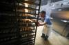 RUTH BONNEVILLE / FREE PRESS
                                49.8 Feature - Hot Cross Buns in the making Photo of lead baker, Julius , moving a full rack of cross buns into the oven Wednesday.