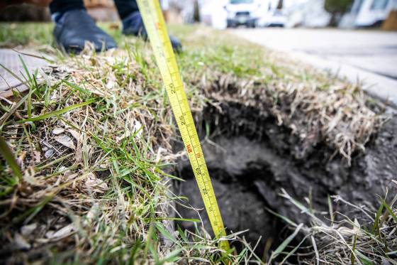 Grace Livingston shows the depth of a hole on the boulevard on Valour Road on Wednesday. (Mikaela MacKenzie / Free Press)
