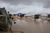 Palestinians walk through a flooded area in a temporary tent camp after heavy rainfall in Gaza City, Thursday, March 26, 2026 (AP Photo/Jehad Alshrafi)