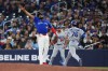 Toronto Blue Jays first baseman Vladimir Guerrero Jr. (left) can't get to ball thrown by pitcher Kevin Gausman (not shown) as Los Angeles Dodgers' Alex Freeland (76) reaches on a bunt during third inning MLB baseball action in Toronto on Tuesday, April 7, 2026. THE CANADIAN PRESS/Nathan Denette
