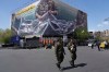 FILE - Two police officers walk in front of an anti-U.S. billboard depicting American aircraft being caught by Iranian armed forces in a fishing net beneath the words in Farsi, 