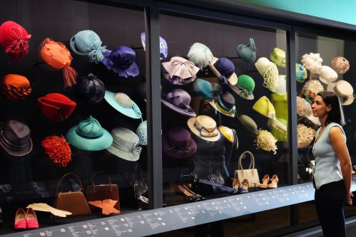 A member of the Royal Collection Trust staff looks towards hats, bags and shoes worn by Princess Elizabeth, on display at 'Queen Elizabeth II: Her Life in Style' exhibition, to mark the centenary of the late queen's birth, at The King's Gallery at Buckingham Palace in London, Thursday, April 9, 2026. (AP Photo/Kirsty Wigglesworth)