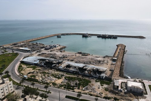 Backdropped by ships in the Strait of Hormuz, damage caused according to local witnesses by recent airstrikes is seen on a fishing pier in the port of Qeshm Island, Iran on Monday, April 13, 2026. (AP Photo/Asghar Besharati)