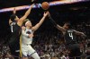 Golden State Warriors guard Brandin Podziemski, second from left, drives between Phoenix Suns guard Devin Booker (1) and guard Jalen Green (4) during the first half of an NBA basketball play-in tournament game, Friday, April 17, 2026, in Phoenix. (AP Photo/Rick Scuteri)